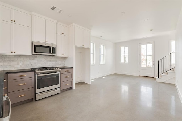 kitchen featuring baseboards, appliances with stainless steel finishes, dark countertops, and a healthy amount of sunlight