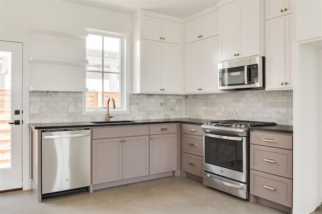 kitchen featuring dark countertops, tasteful backsplash, open shelves, a sink, and stainless steel appliances