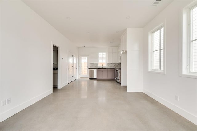 unfurnished living room with a sink, baseboards, finished concrete floors, and visible vents