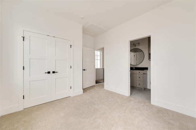 unfurnished bedroom featuring a closet, baseboards, light carpet, and attic access