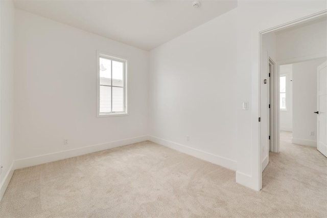 spare room featuring baseboards and light colored carpet