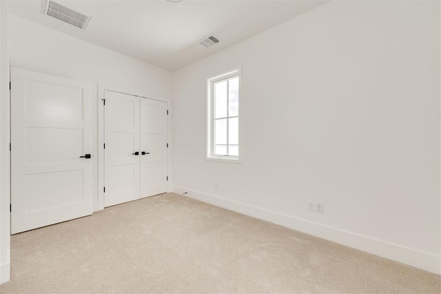 unfurnished bedroom with visible vents, baseboards, a closet, and light carpet