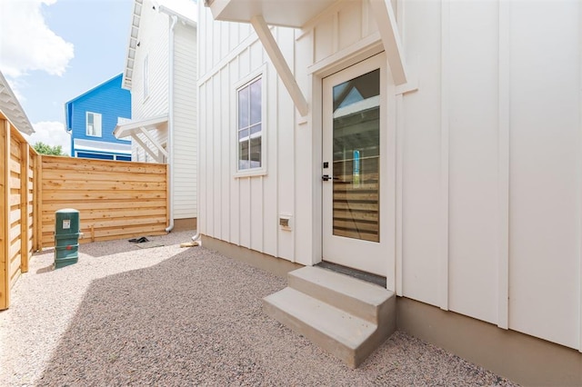 property entrance featuring board and batten siding and fence