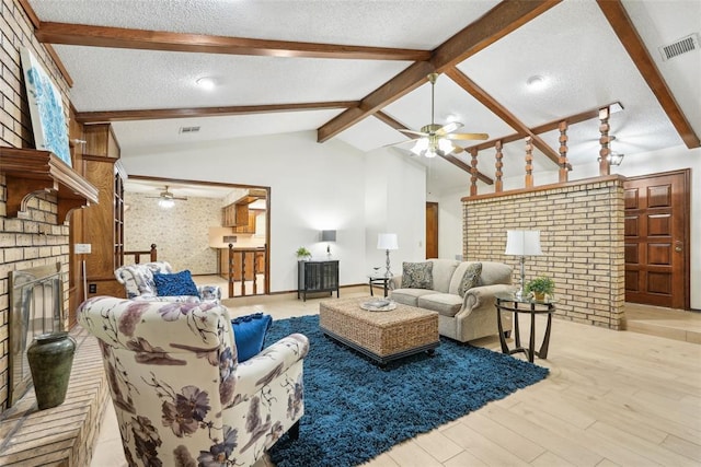 living room with vaulted ceiling with beams, ceiling fan, a fireplace, and visible vents