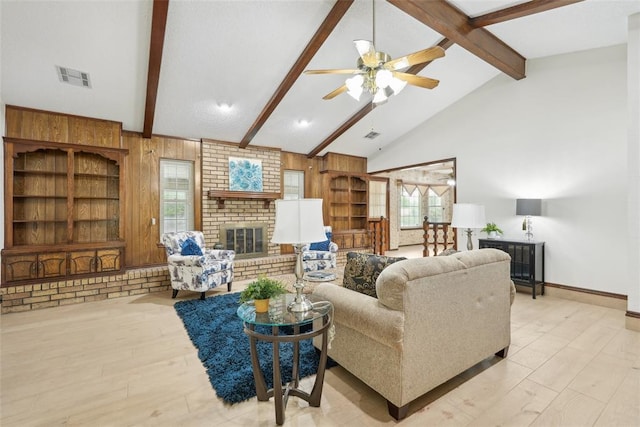 living area featuring a ceiling fan, beamed ceiling, visible vents, and wood finished floors