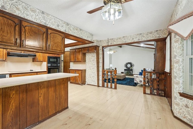 kitchen with a ceiling fan, light wood finished floors, black appliances, and wallpapered walls