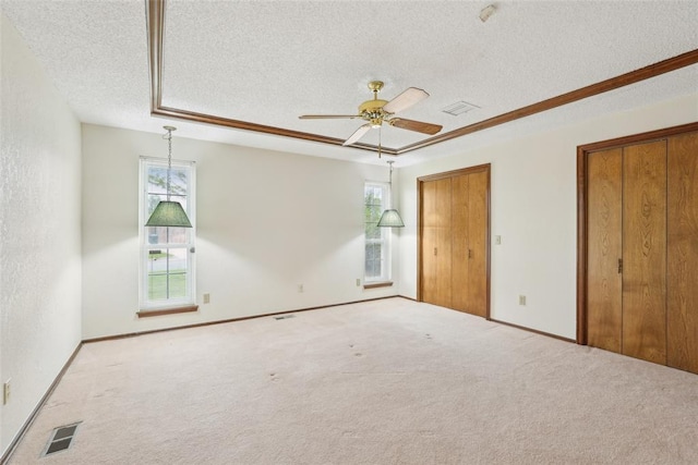 unfurnished bedroom featuring ceiling fan, carpet floors, a textured ceiling, two closets, and visible vents