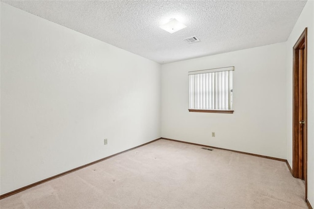 unfurnished bedroom with baseboards, light colored carpet, a textured ceiling, and visible vents
