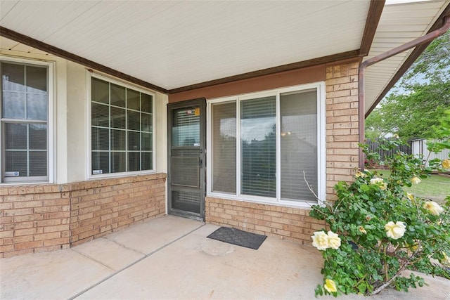 property entrance featuring brick siding, a patio area, and fence