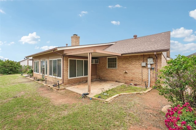 rear view of property with a lawn, a chimney, a patio area, and brick siding
