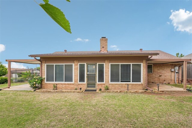 rear view of property with brick siding, a patio area, a lawn, and a chimney