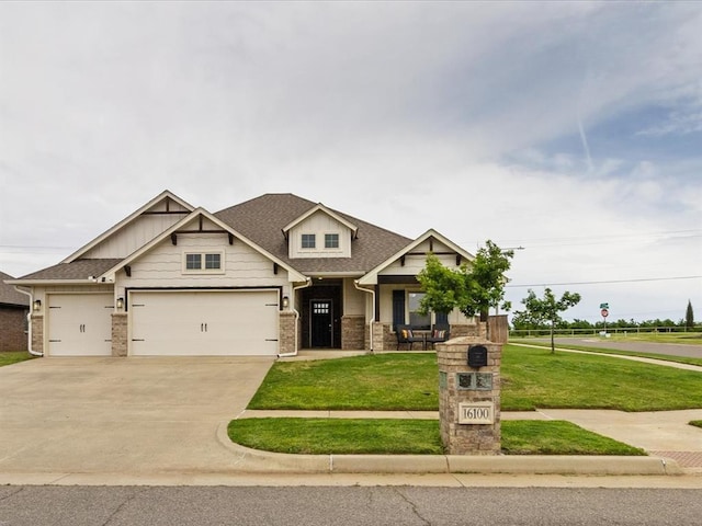 craftsman house featuring brick siding, driveway, a garage, a front yard, and a shingled roof