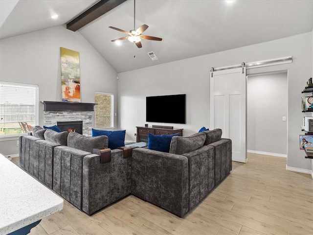 living area with a ceiling fan, a barn door, light wood finished floors, high vaulted ceiling, and beam ceiling