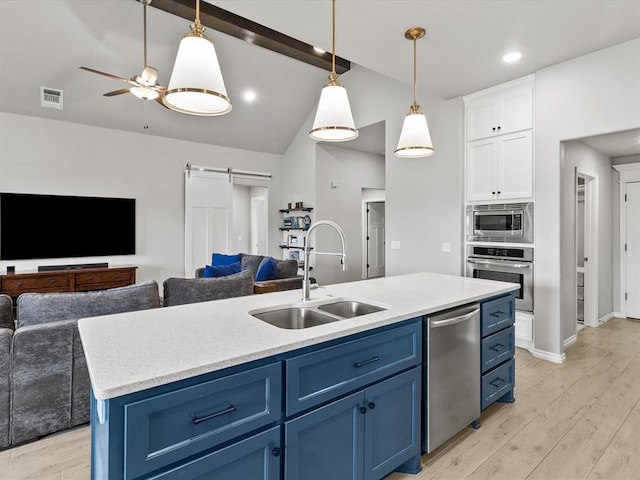 kitchen with a sink, a barn door, visible vents, blue cabinetry, and appliances with stainless steel finishes