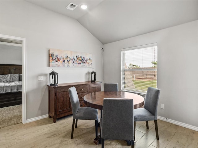 dining room with baseboards, visible vents, light wood-style flooring, and lofted ceiling