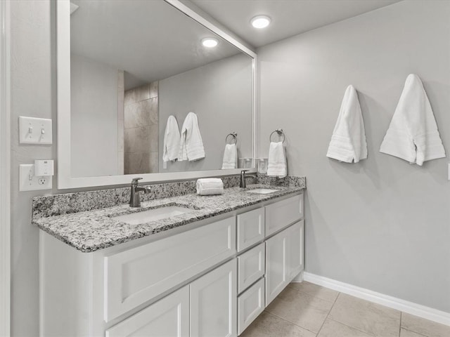 bathroom featuring baseboards, tile patterned floors, double vanity, and a sink