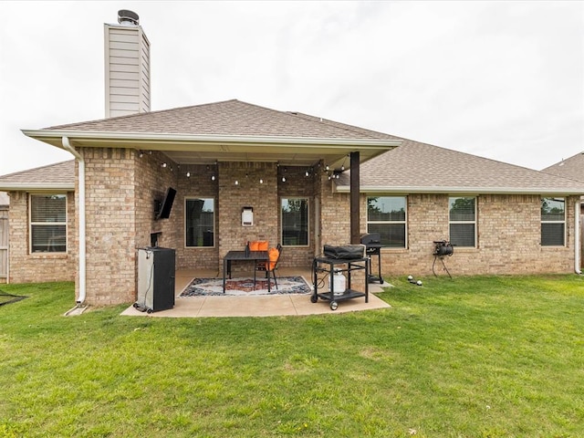 back of property with a shingled roof, a patio, and a yard