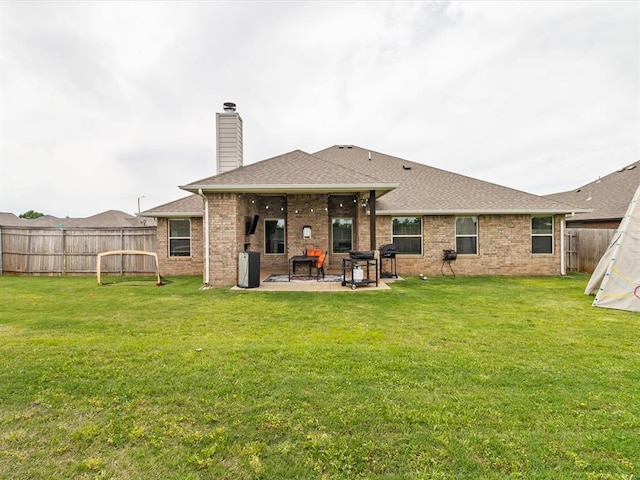 back of property with a chimney, brick siding, a patio, a shingled roof, and a fenced backyard