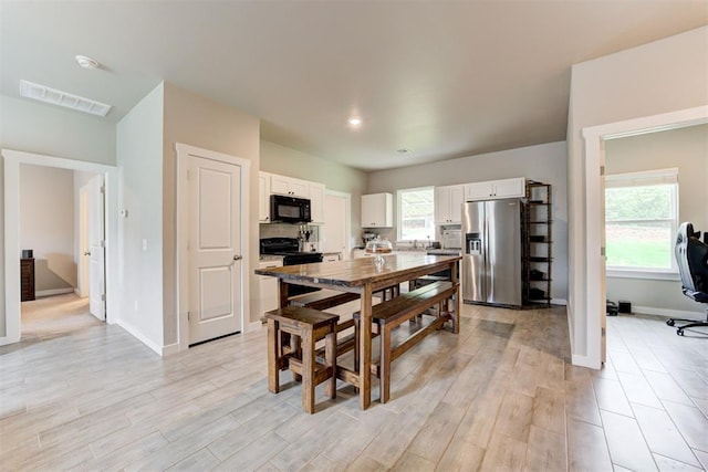 dining area with baseboards, light wood finished floors, and visible vents