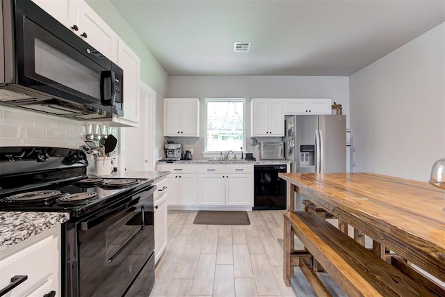 kitchen featuring visible vents, white cabinets, light stone counters, backsplash, and black appliances