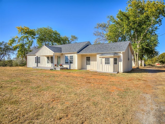 ranch-style house with board and batten siding, a shingled roof, and a front yard