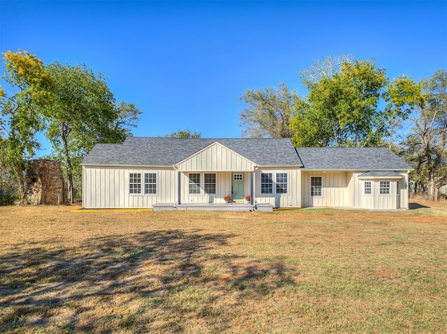 view of front of home with roof with shingles, board and batten siding, and a front yard