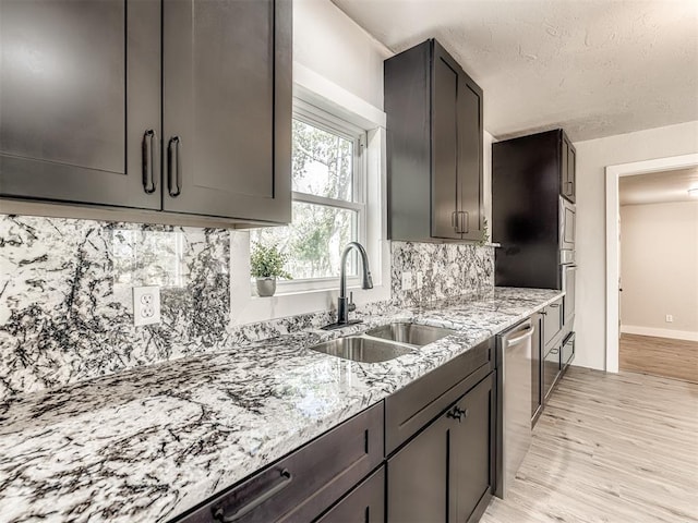kitchen featuring a sink, light stone counters, decorative backsplash, and stainless steel dishwasher