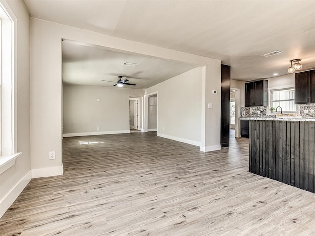unfurnished living room with baseboards, visible vents, ceiling fan, and light wood finished floors