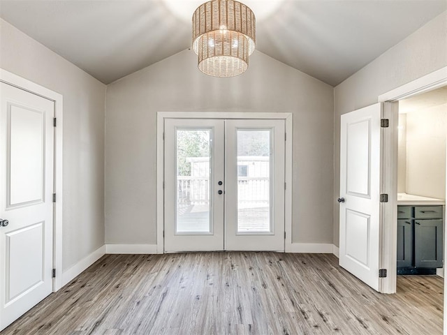 doorway to outside featuring light wood-style floors, baseboards, lofted ceiling, and a notable chandelier