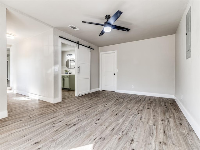 interior space with a ceiling fan, baseboards, a barn door, and light wood-type flooring