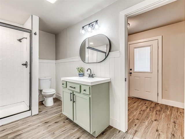 full bath with a wainscoted wall, a stall shower, and wood finished floors