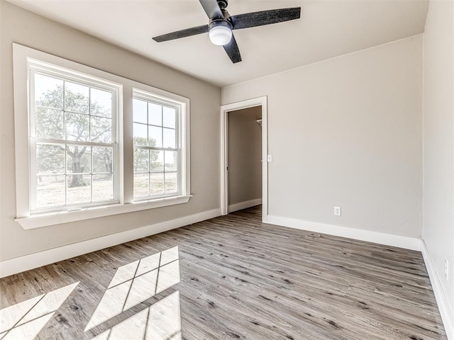 unfurnished room featuring baseboards, a ceiling fan, and wood finished floors