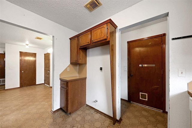 208 Harrogate Dr, Yukon, OK 73099 - kitchen with tile patterned floors, brown cabinets, a textured ceiling, and baseboards