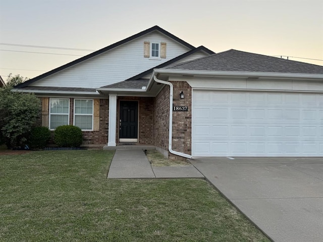 view of front of house featuring driveway, roof with shingles, a garage, brick siding, and a front lawn