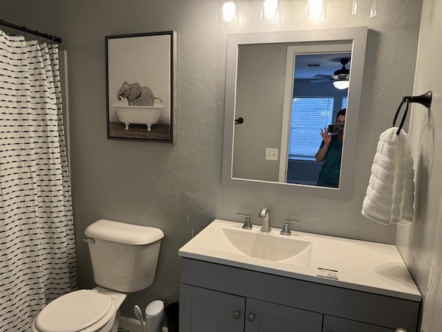 bathroom featuring vanity, a textured wall, a ceiling fan, and toilet
