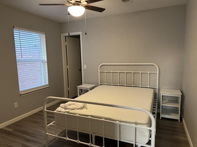 bedroom with baseboards, multiple windows, a ceiling fan, and dark wood-type flooring