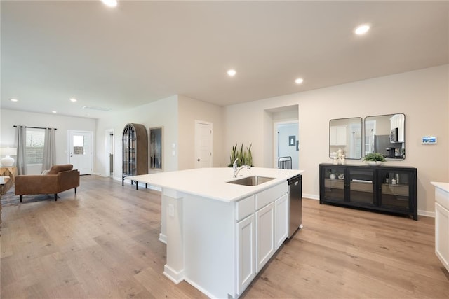 kitchen with light countertops, white cabinets, light wood-type flooring, and a sink