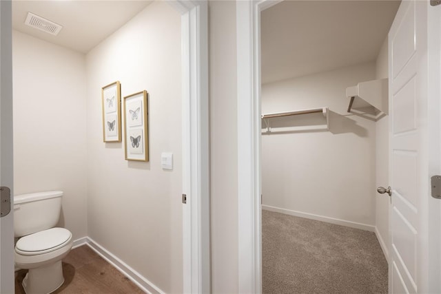 bathroom featuring baseboards, toilet, and visible vents