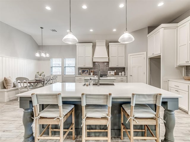 kitchen featuring light wood-style floors, premium range hood, recessed lighting, a wainscoted wall, and tasteful backsplash