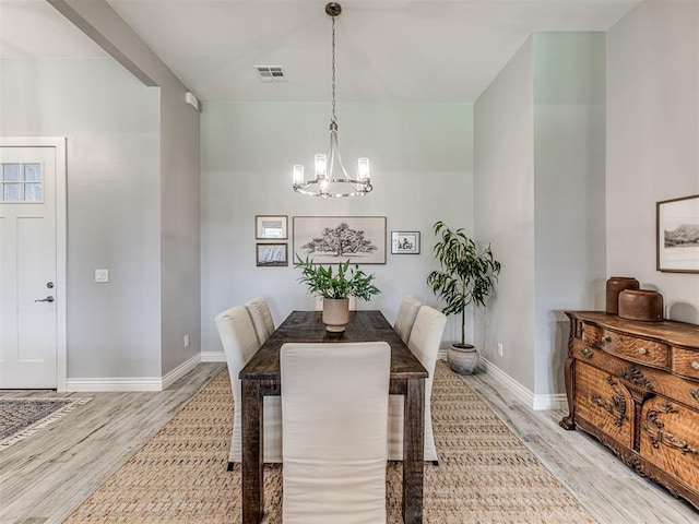 dining area featuring an inviting chandelier, baseboards, light wood-style flooring, and visible vents