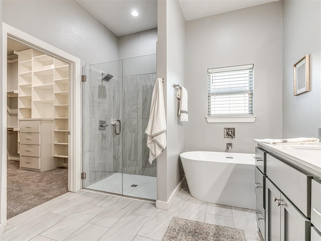 full bath featuring vanity, a soaking tub, a shower stall, and a spacious closet