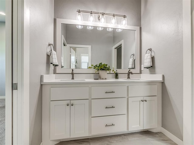 full bath with a sink, baseboards, double vanity, and marble finish floor