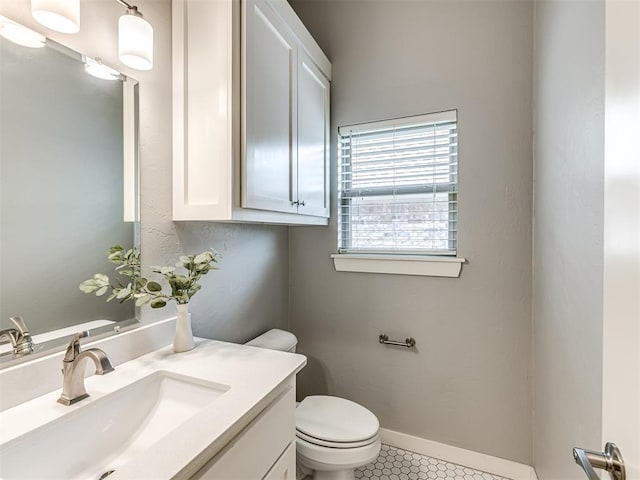 half bathroom featuring vanity, tile patterned flooring, baseboards, and toilet