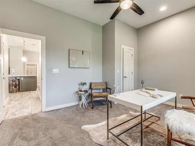 office with a ceiling fan, baseboards, light carpet, and a sink
