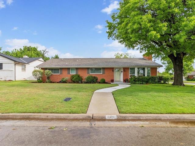 ranch-style house featuring brick siding, a chimney, and a front yard