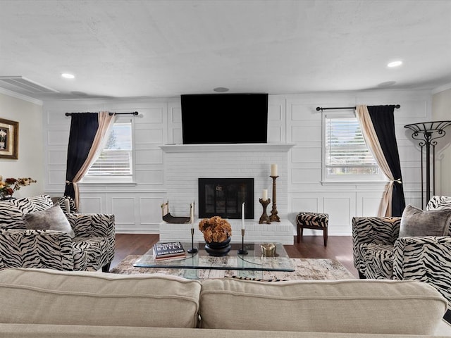 living room featuring crown molding, a brick fireplace, wood finished floors, and a wealth of natural light