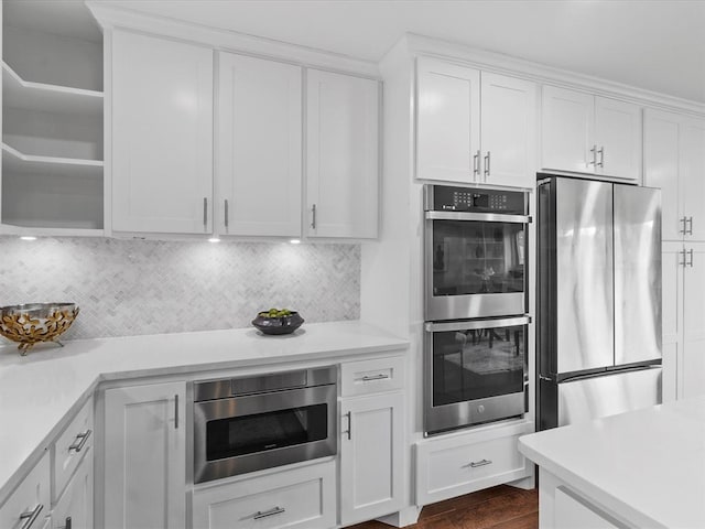 kitchen with light countertops, white cabinets, tasteful backsplash, dark wood finished floors, and appliances with stainless steel finishes