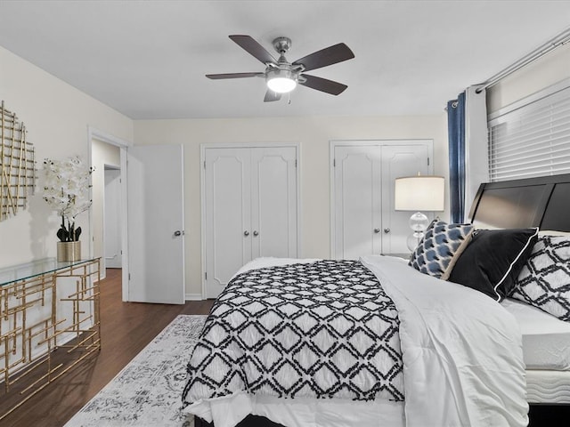bedroom featuring ceiling fan, two closets, and dark wood-style floors