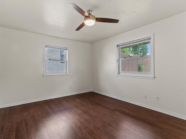 spare room with baseboards, a ceiling fan, wood finished floors, and a wealth of natural light