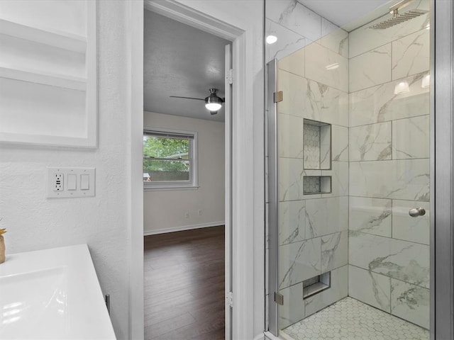 full bathroom with ceiling fan, a marble finish shower, baseboards, and wood finished floors